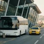Shuttle bus and taxi outside Tirana International Airport arrivals terminal with travellers and luggage